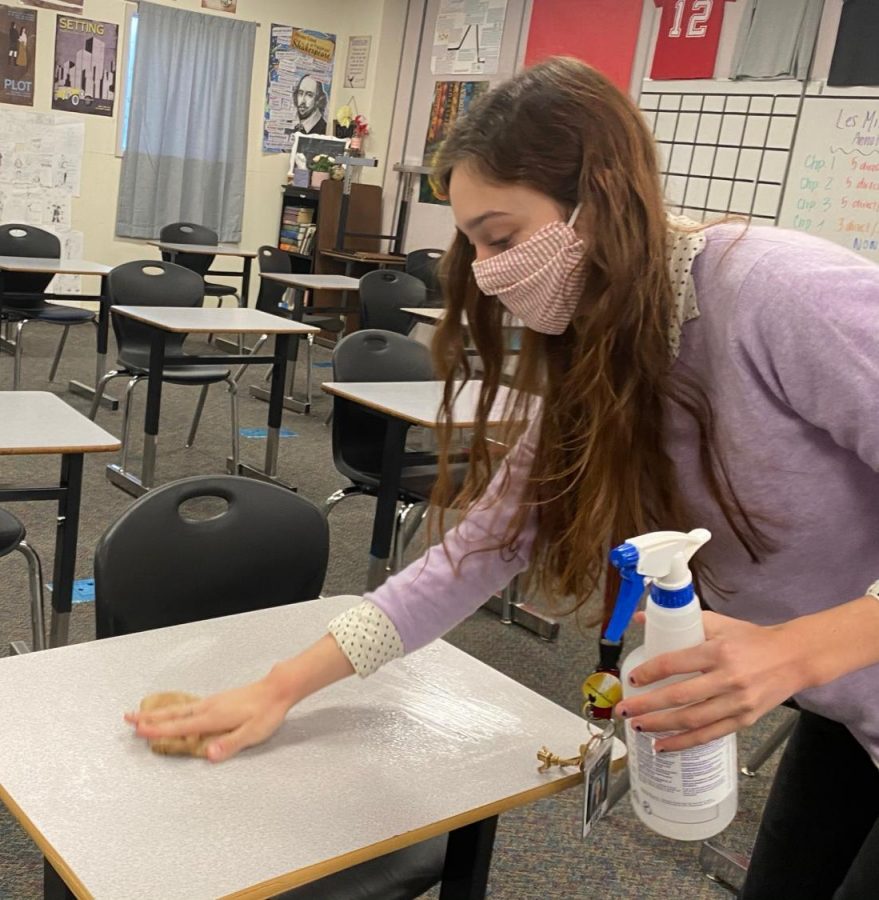 A NEW TYPE OF SCHOOL PREP: Before her first period of the day starts, DM English Teacher Ms. Jongewaard wipes every desk in her classroom. “For the most part, I’m always able to get it done,” Ms. Jongewaard said, though for later periods she sometimes has “to take the first couple of minutes of class.” Additionally, Ms. Jongewaard has a hand-sanitizing station at the entrance to her classroom.