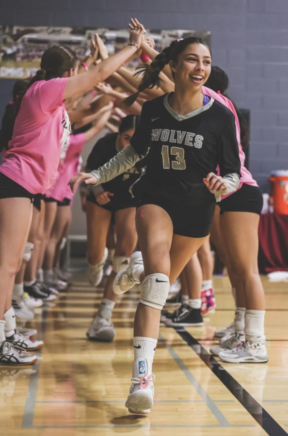 SMILING INTO THE COMPETITION-Sophia Hartel (12) sprints through the tunnel before DMs 3-1 victory against Saguaro in September. Seeing all the fans was an amazing feeling, said Hartel, who plays both setter and defensive specialist. All that support for our team and spirit felt awesome. DM volleyball ended the season ranked 14th overall in the state.