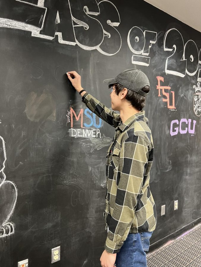 COLLEGE BOUND: Jake Magluyan (12) writes his name and prospective college, Scottsdale Community College, on Mrs. Dorsch’s college wall. Its a great way to see where your peers end up next year Magluyan said. The college wall has been a tradition at Desert Mountain since 2020, allowing seniors to bask in their achievements and see where their peers are heading.  
